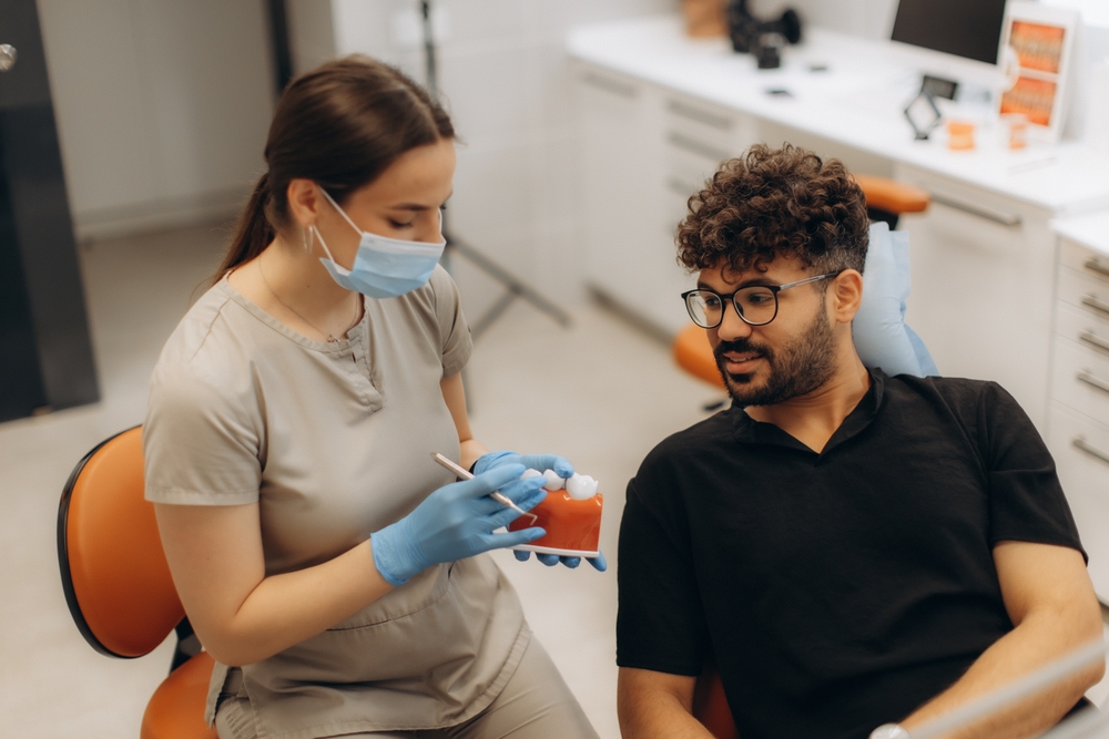 Dental professional explaining a dental bridge model to a patient, emphasizing clear communication and customized tooth replacement options – Dental Bridges in Austin