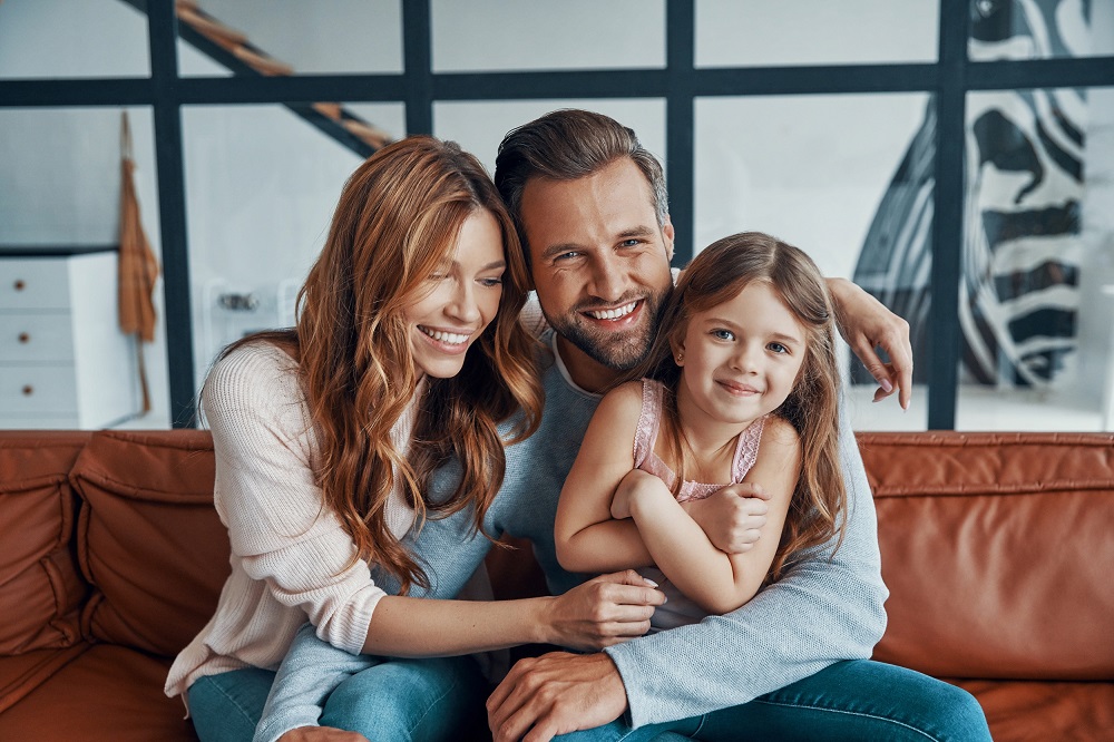 A smiling family relaxing together in a warm, modern setting, representing trust, comfort, and confident smiles achieved through family-focused dental care – Dentist Austin TX