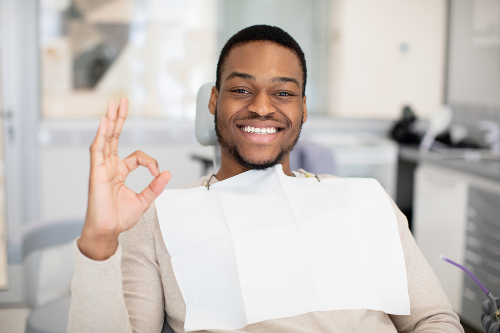 Happy Patient After Invisalign Treatment – Invisalign in Austin, Texas Smiling patient seated in a dental chair giving an OK sign, expressing satisfaction with Invisalign orthodontic care – Invisalign in Austin, Texas