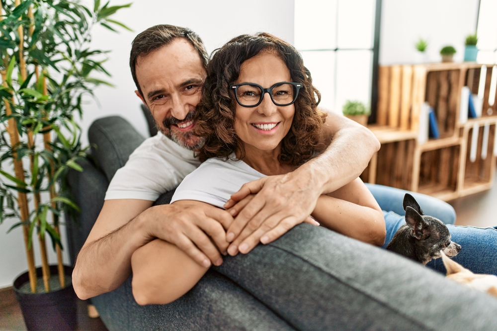 A happy couple relaxing together in a cozy home setting, representing comfort, trust, and confident smiles achieved through personalized, patient-centered dental care – Dentist Dripping Springs TX