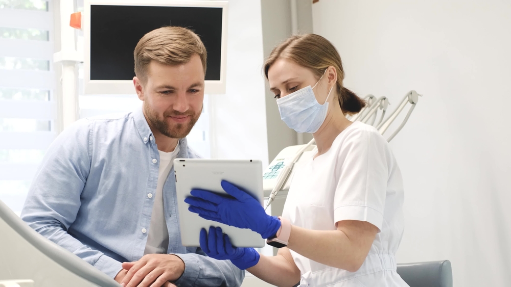 Dentist Using Tablet to Explain Digital Treatment Results – Technology Dental professional using a tablet to explain digital treatment results, highlighting technology-driven communication and patient care – Technology