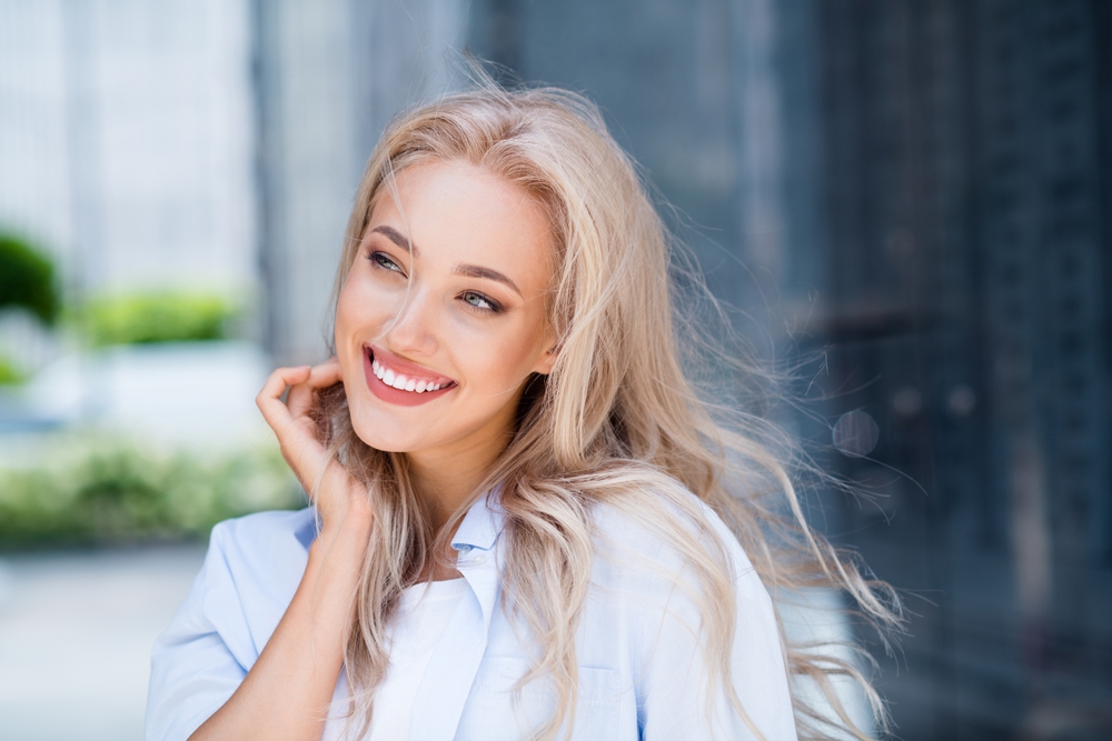 Radiant Smile After Professional Teeth Whitening – Teeth Whitening in Austin Woman smiling confidently outdoors, showcasing a bright, refreshed smile achieved through professional teeth whitening treatment – Teeth Whitening in Austin