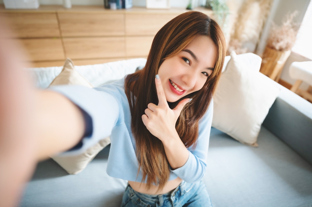 Young woman taking a selfie while smiling confidently, reflecting the results of high-quality dental crown restoration – Austin TX Dental Crowns